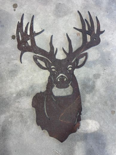 Metal deer head silhouette art on a concrete surface.