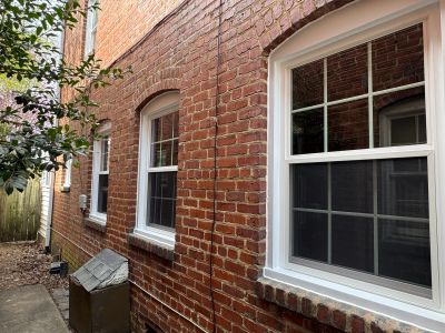 Brick building with white-framed windows along a narrow path.