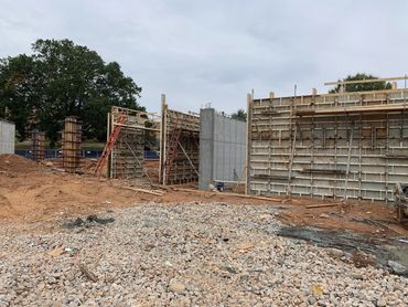 Construction site with concrete walls and scaffolding under cloudy sky.