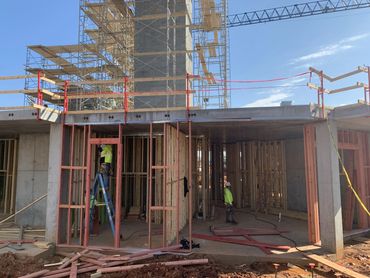 Construction workers framing a building under clear blue sky.