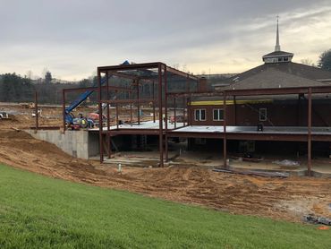 Steel framework of a building under construction next to an existing church structure.