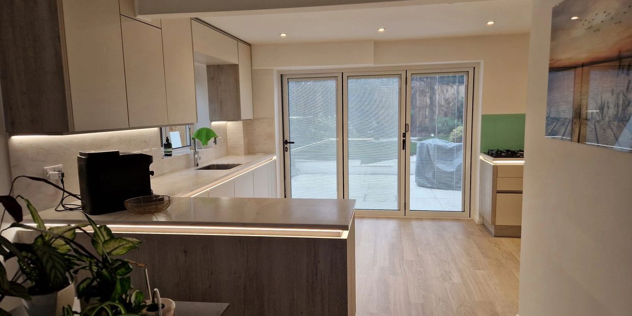 A modern handle-less kitchen design with corian worktops and glass splashback