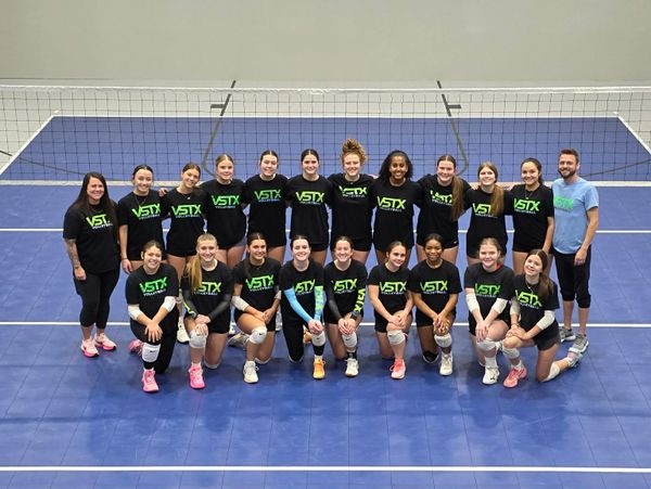 A volleyball team posing on the court wearing matching VSTX shirts.
