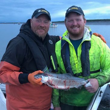 Two fishermen proudly holding a freshly caught fish on a boat.