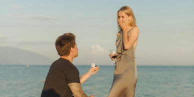 Man proposes to woman on the beach during sunset.