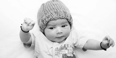 A baby wearing a knitted hat and a printed shirt.