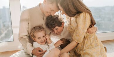 A joyful family cuddles together in a cozy, sunlit room.