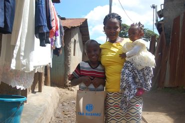 A woman with two children standing outdoors in a residential area.