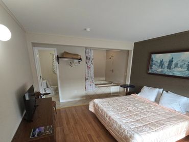 Simple hotel room with a bed, TV, and open bathroom area.