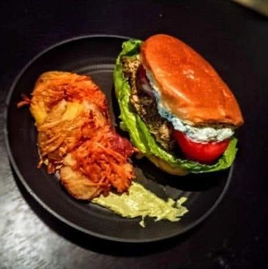 Greek chicken sandwich with Tzatziki sauce and side of crispy smashed potatoes