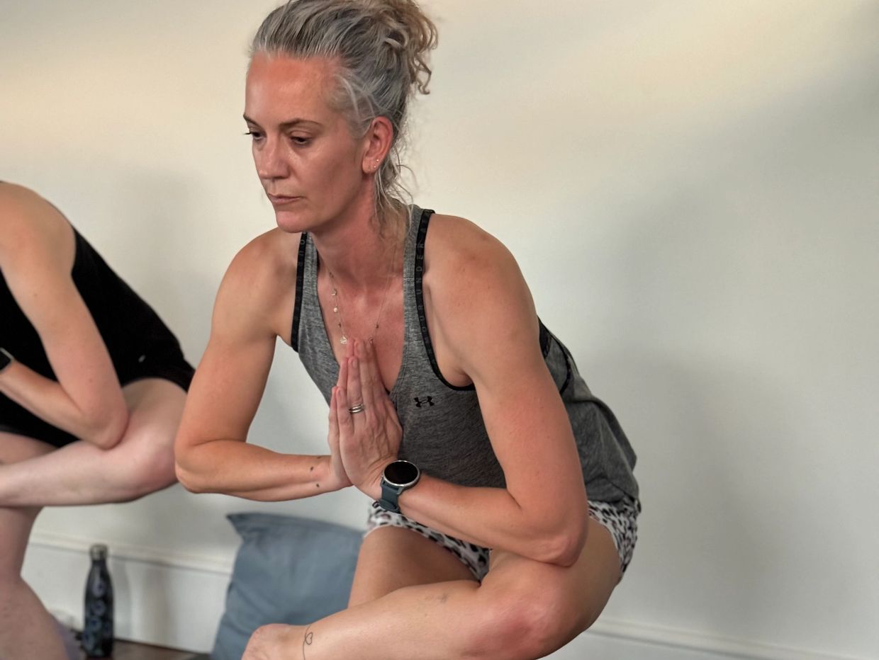 Woman practicing yoga balance pose indoors.