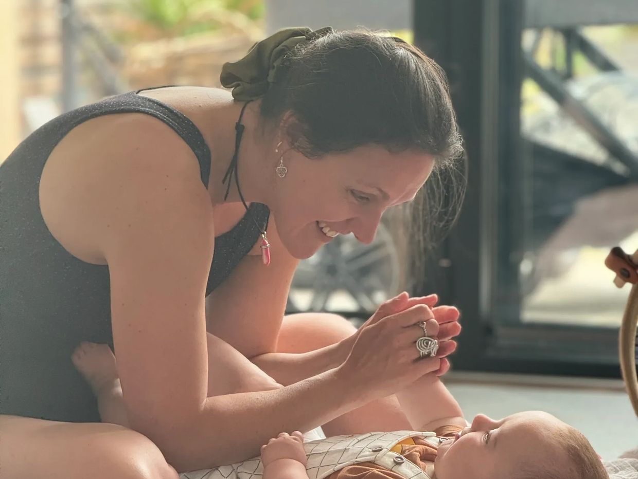 Woman smiling and playing with a baby.