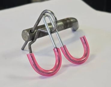 Metal puzzle with pink plastic-covered hooks on a white surface.