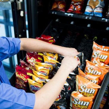 person's hands refilling a snack machine
