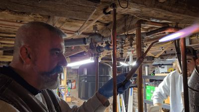 Liberty Plumbing technician soldering pipes during a water heater service call