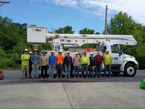 Group of utility workers standing in front of a bucket truck.