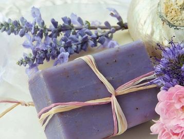 Purple lavender soap tied with twine surrounded by flowers and a shell.