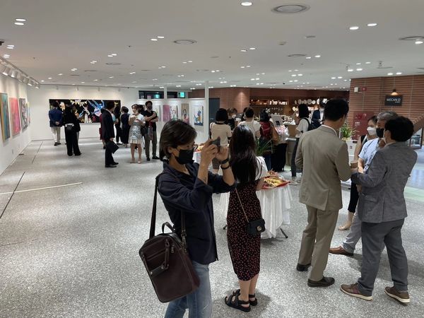 People viewing and photographing art in a well-lit gallery space.