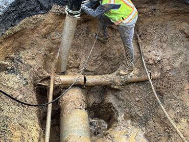Man hydro excavating around a broken pipe for replacement.