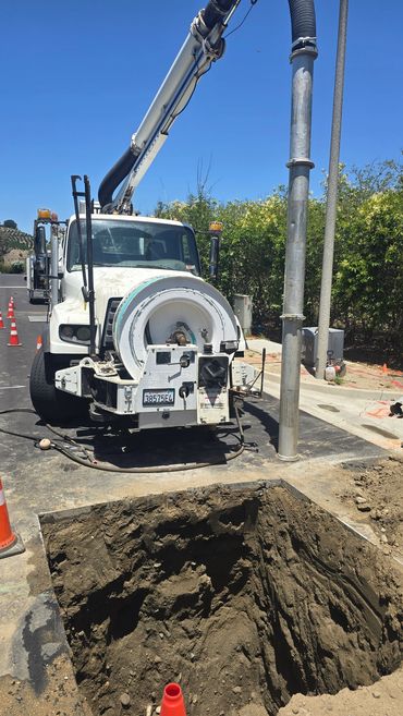 Jet vac truck in front of hydro excavated hole for pipe repair.