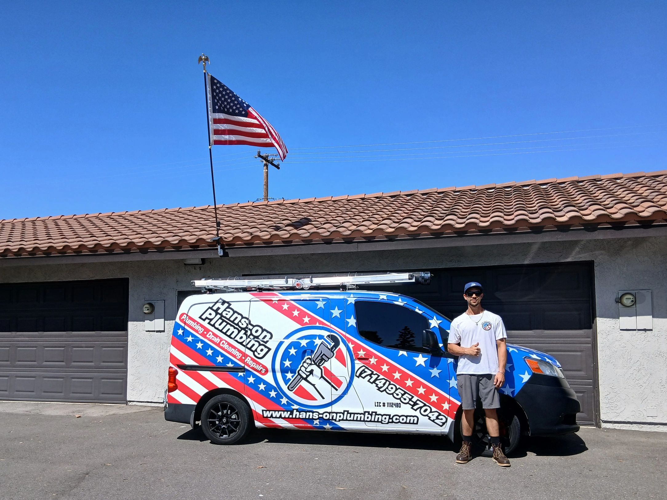 Plumber standing beside a patriotic-themed van with an American flag.