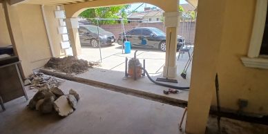 Home patio under renovation with concrete cut open and trended for slab leak repair and reroute