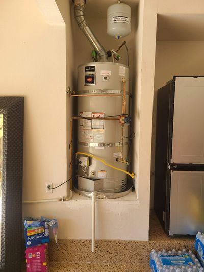 Water heater installed in a wall niche with pipes and valves.