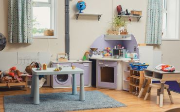 Playroom with toy kitchen and table setup.