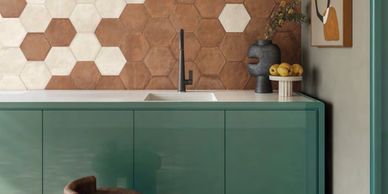 Modern kitchen with hexagonal tile backsplash and green cabinetry.