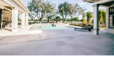 Luxurious backyard with pool and spacious patio area under clear sky.