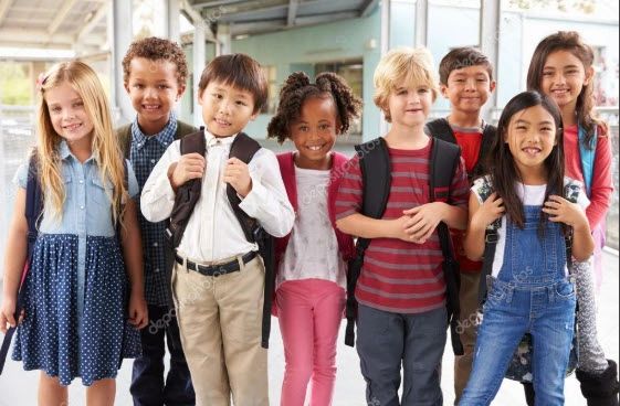A diverse group of seven smiling schoolchildren with backpacks.