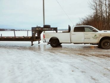 White pickup truck with trailer on icy ground in winter.