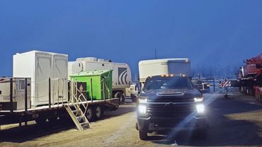 Nighttime construction site with vehicles and portable light tower.