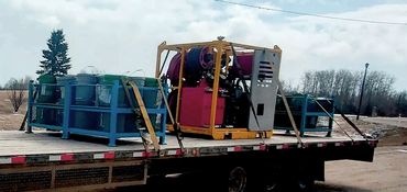 Flatbed trailer loaded with equipment attached to a white pickup truck.