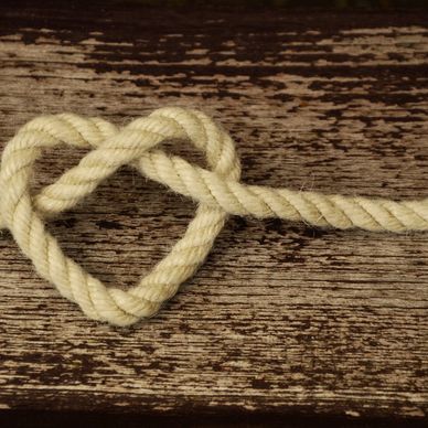 Rope twisted into a heart shape on a wooden surface.