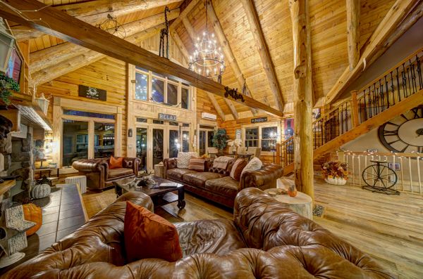 Cozy rustic cabin living room with wooden beams and leather sofas.