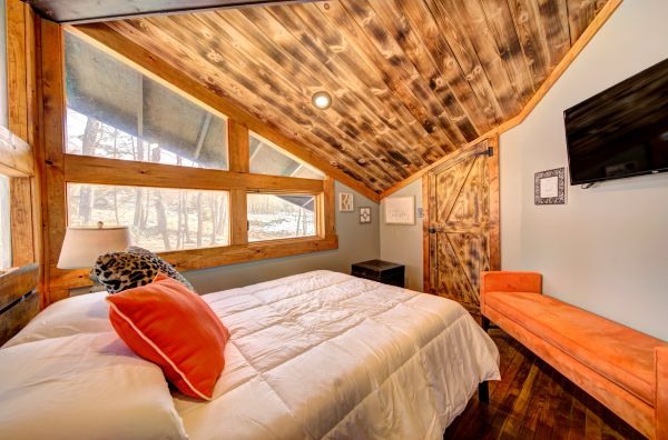 Cozy bedroom with wooden ceiling and orange accents.