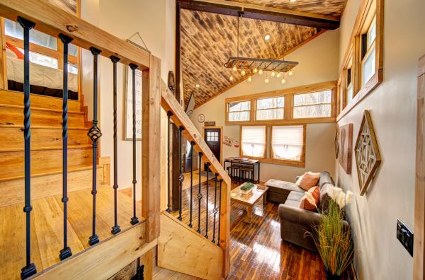 Cozy wooden cabin interior with a staircase, sofa, and large windows.