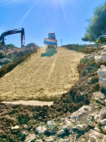 Tractor creating road on a hill. This road will hold up over time to all weather and water.