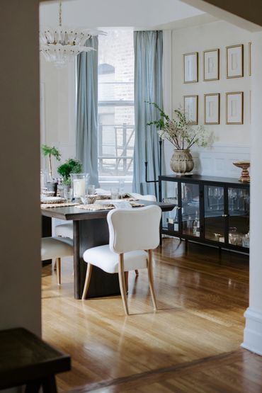 Elegant dining room with white chairs and floral centerpiece on table.