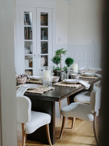 Elegant dining table set with plants and candles in a cozy room.