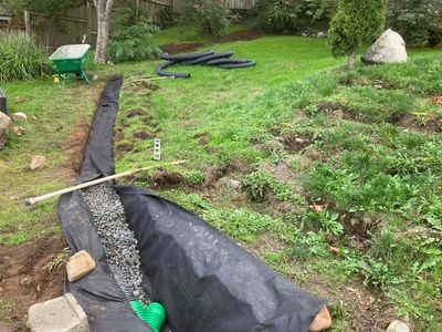 Drainage installation with gravel and pipes in a garden.