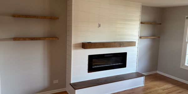 Modern fireplace with wooden shelves and bench in a living room.