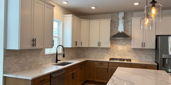 Modern kitchen with white and wood cabinets and marble countertops.