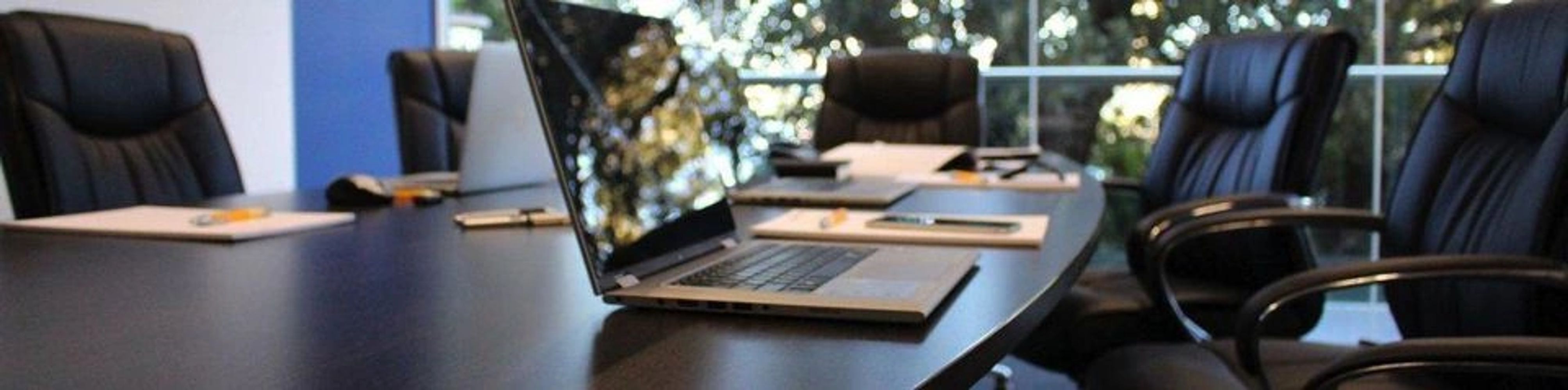 Modern conference room with a sleek laptop and black leather chairs.