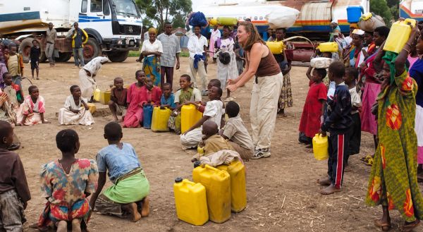 People gathered with yellow water containers in a busy outdoor setting.