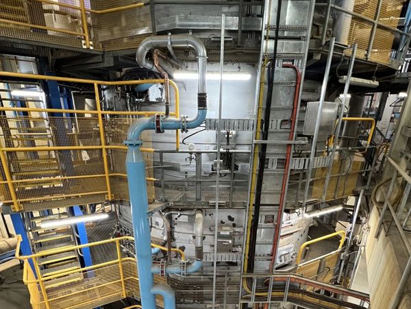 Industrial facility with metal pipes and yellow safety railings.