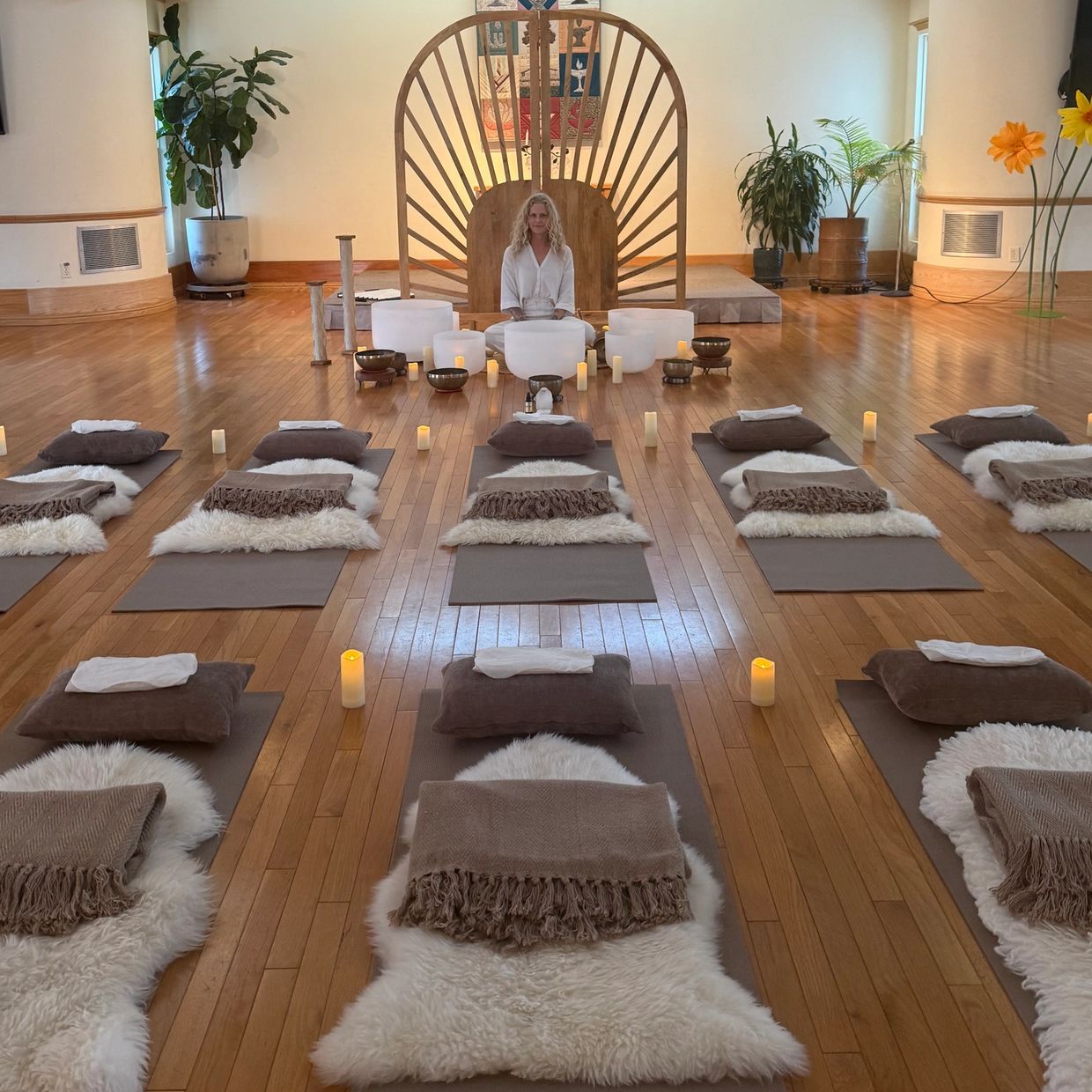 Woman sitting in a serene meditation room with candles and cushions.