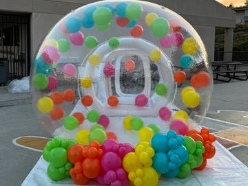8ft bubble house with an array of tropical colored balloons floating inside