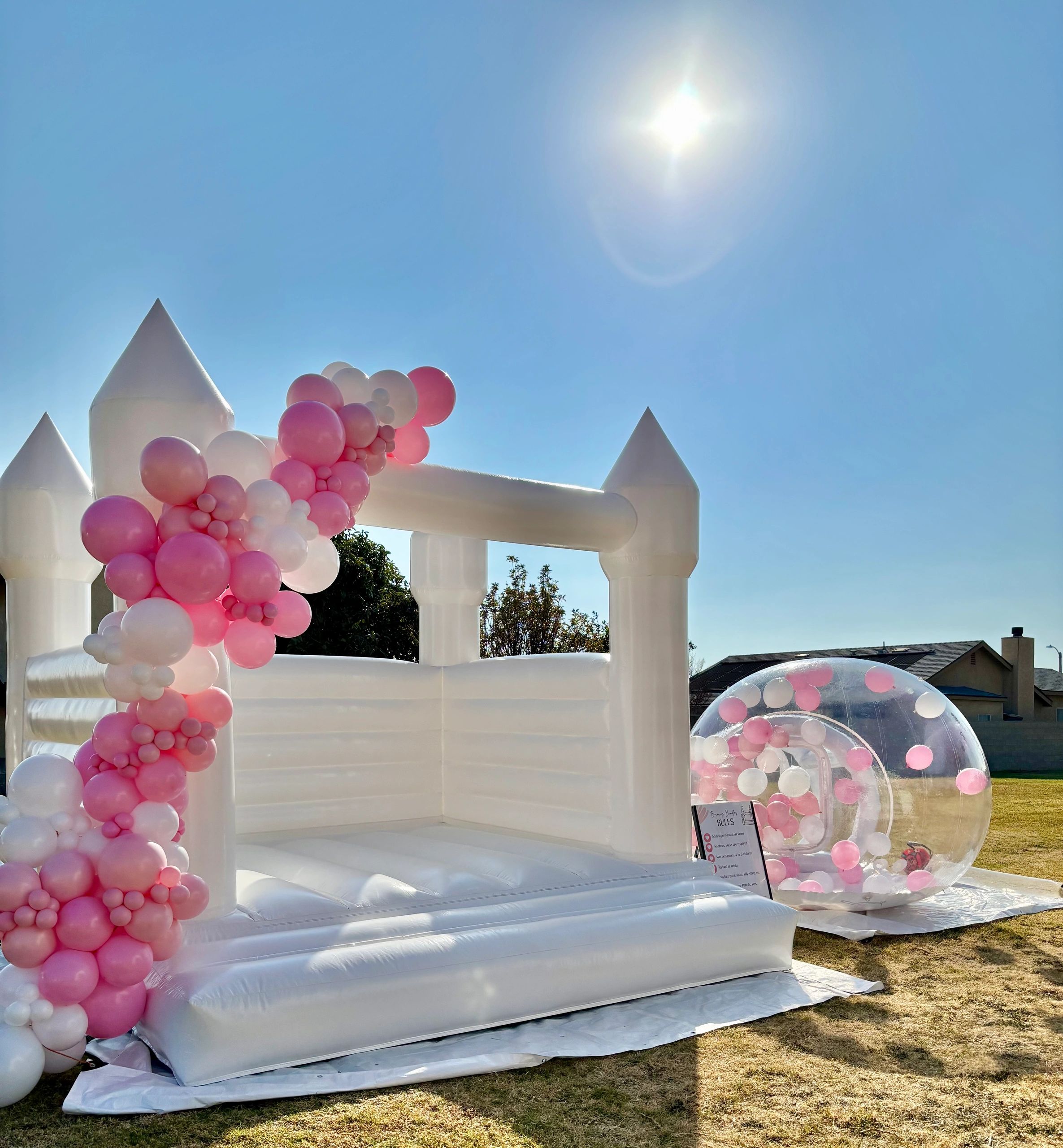 13x13 all white bounce house with pink and white balloons cascading down the front. Bubble house wit